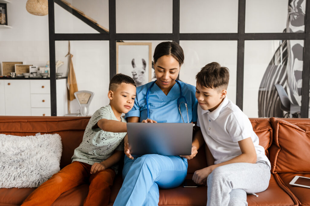 Black woman doctor and her sons using laptop while sitting on couch in home